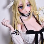 Anime-style doll with long blonde hair and blue eyes, wearing a white lace dress with a black bow and lace headband, holding pale flowers.