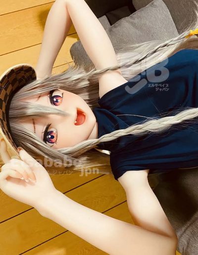 Anime-style doll with long silver hair and pink eyes lying on a wooden floor, wearing a navy shirt and a straw hat.
