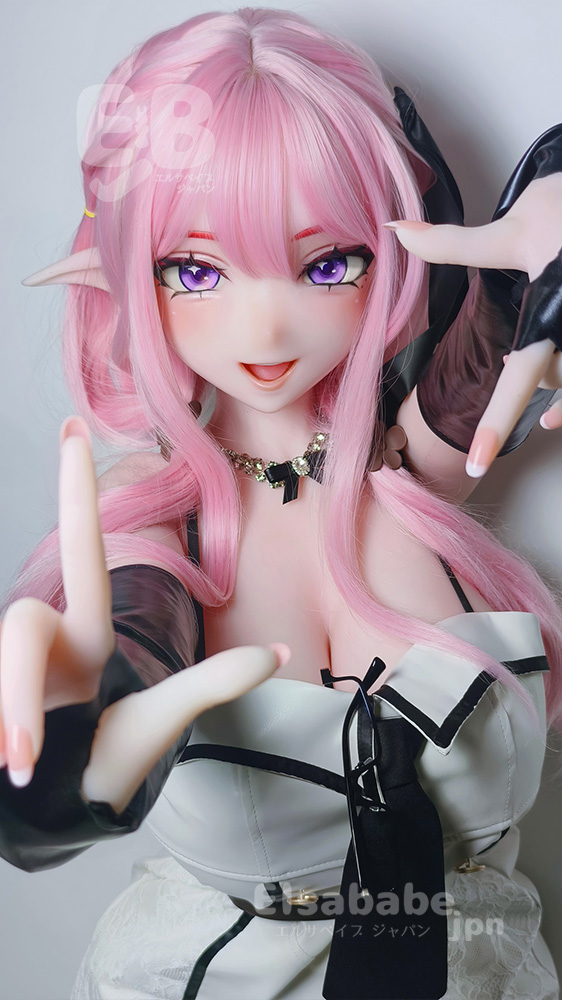 Close-up of a pink-haired anime-style doll with elf ears, wearing a black-and-white outfit and posing with outstretched hands toward the camera.