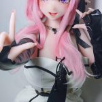 Anime-style doll with pink hair and elf ears wearing a white dress with black ribbons, posing toward the camera with hands up.