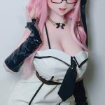 Cosplay doll with long pink hair, glasses, and a white and black dress, posing with a hand near her face.