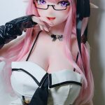 Cosplayer with pink hair and glasses in a white and black-trimmed dress with long black gloves, posing with a finger to the lips.
