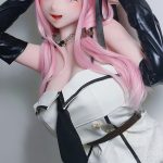 Cosplay doll with pink hair and purple eyes wearing a white dress with black trim and long black gloves, posing playfully against a gray background.