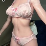 Pink satin lingerie set on a mannequin: lace-trimmed bra with bows and matching panties with a small bow.