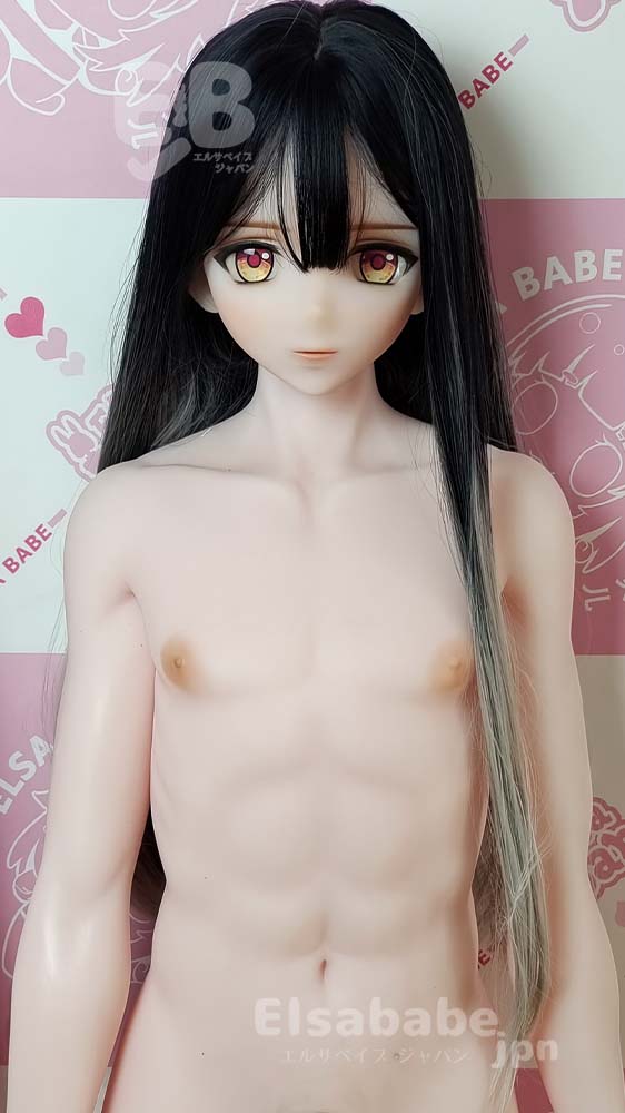 Life-size doll with long black hair and amber eyes, topless torso, standing against a pink patterned background.